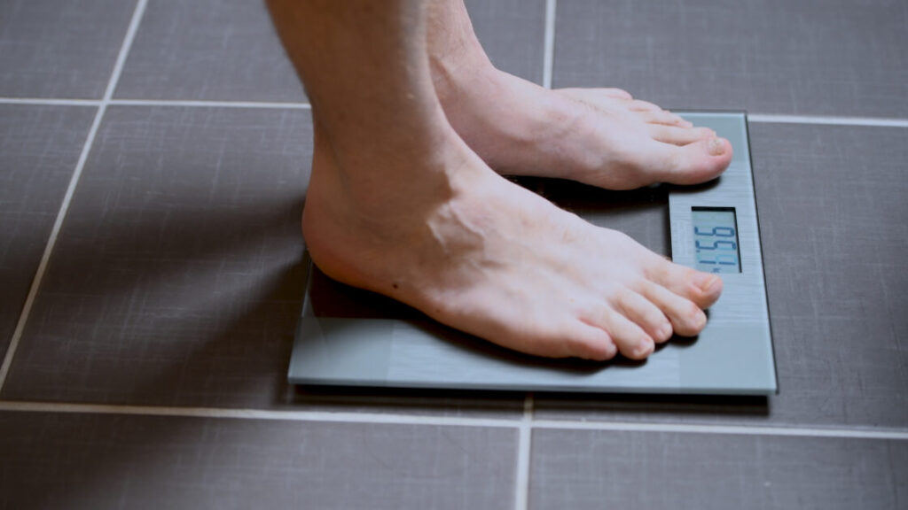 Male feet on glass scales, men's diet, body weight