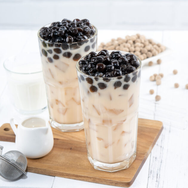 2 glasses of Bubble milk tea with tapioca pearl topping  on wood block