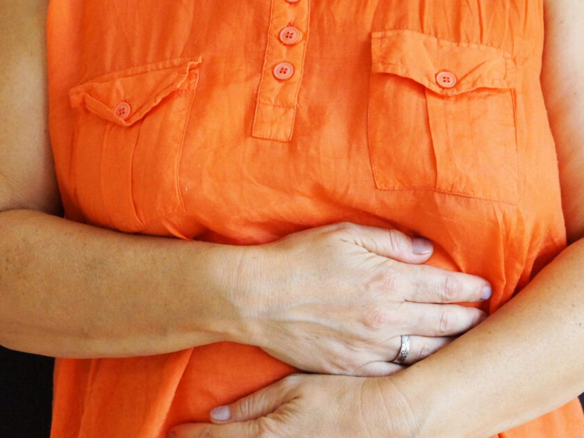 woman holding her sore belly with her hands close up