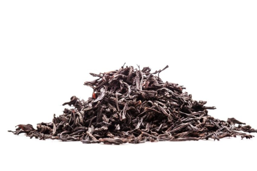 pile of black tea leaves against white background
