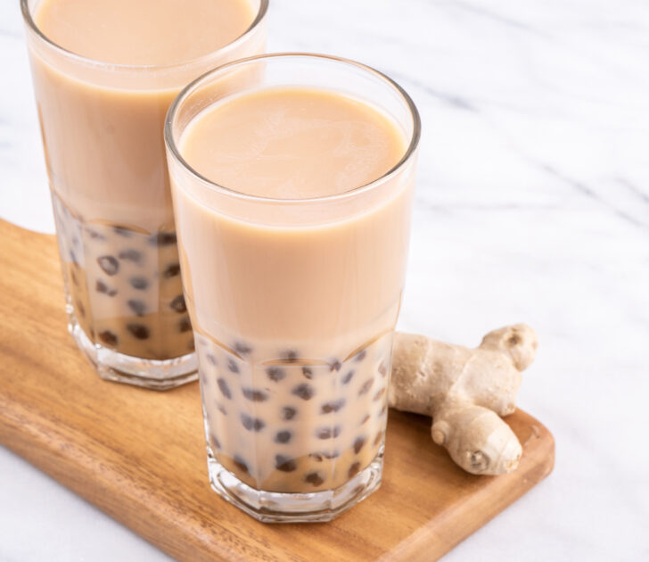 Popular Taiwan drink - Bubble milk tea with tapioca pearl ball in drinking glass on marble white table wooden tray background, close up, copy space