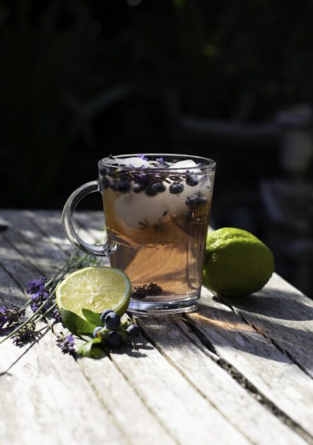 cold refreshing tea with blueberry, lime and lavender on a hot summer day on a wooden table.
