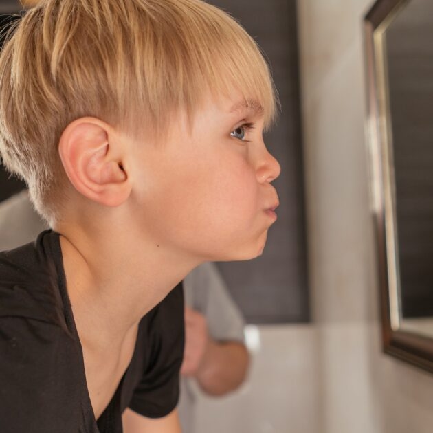 Child gargling salt water, looking in mirror