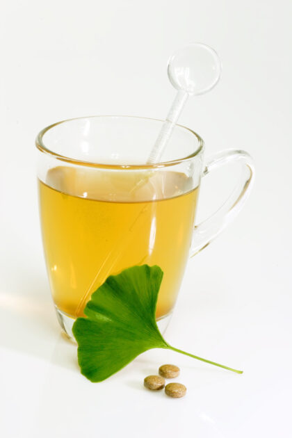Ginkgo Biloba extract pills and fresh Ginkgo Biloba leaves with a glass of Ginkgo tea.