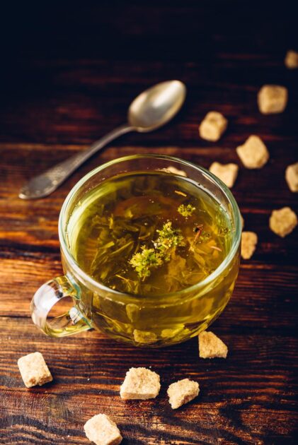 Green tea with brown tea sugar on a wooden background