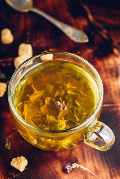Cup of green tea with brown tea sugar on a wooden background