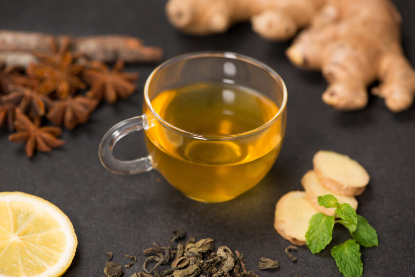 Cup of ginger tea with lemon and honey on dark stone background