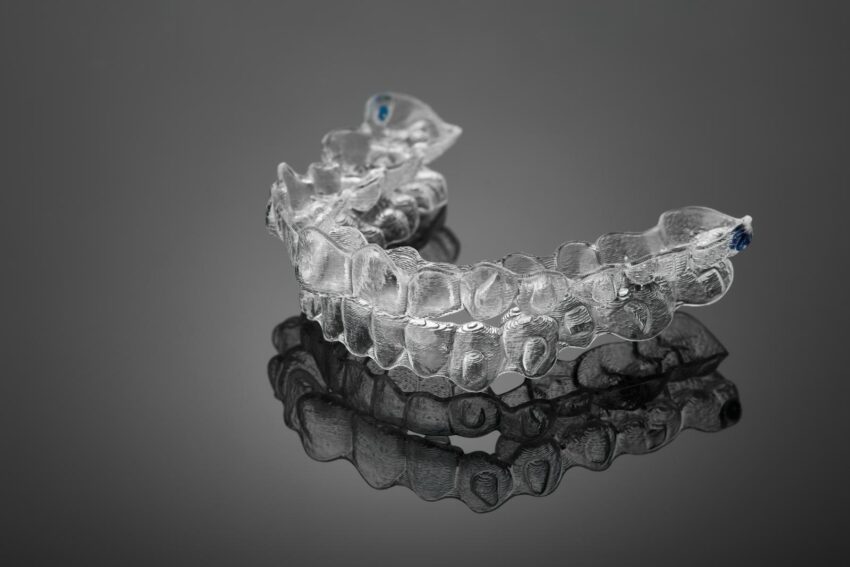 Invisible orthodontics cosmetic brackets on black background, tooth aligners, plastic braces. A way to have a beautiful smile and white teeth.