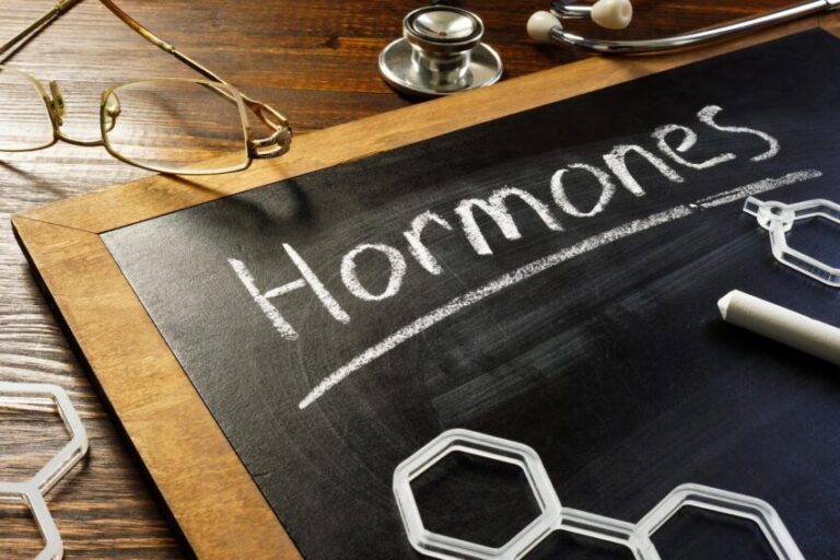 Handwritten word hormones on the blackboard and glasses
