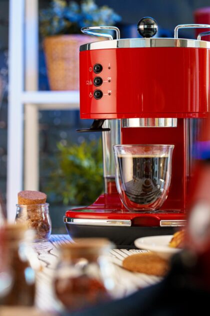 Red coffee machine with a glass on kitchen counter. 