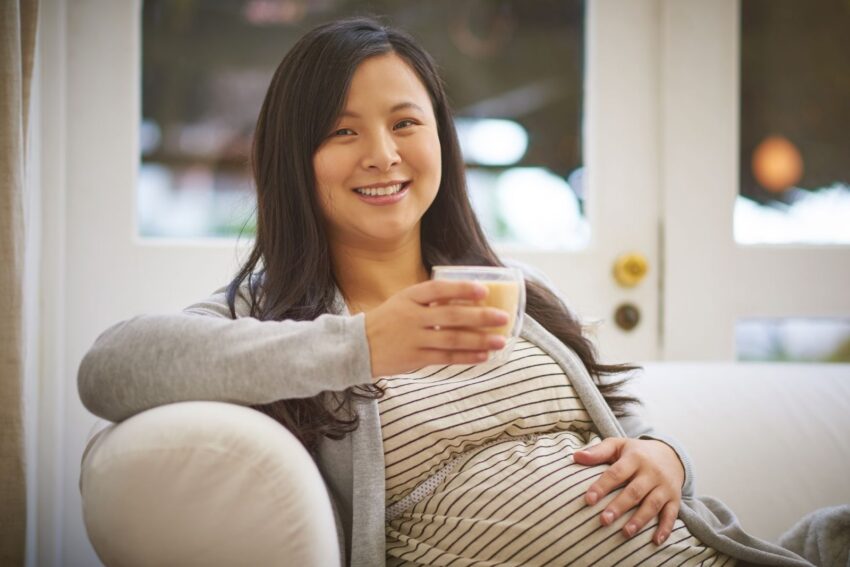 Portrait of an attractive young pregnant woman drinking an iced tea while relaxing on the sofa at home