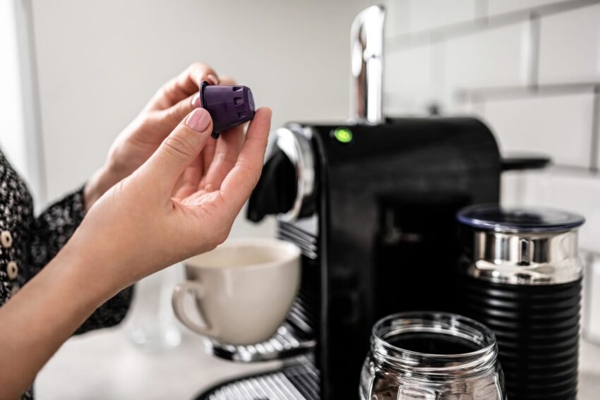 Girl hand put capsule to coffee machine at home 