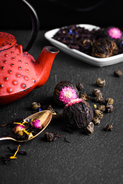 Red teapot and varieties of loose leaf and blooming tea