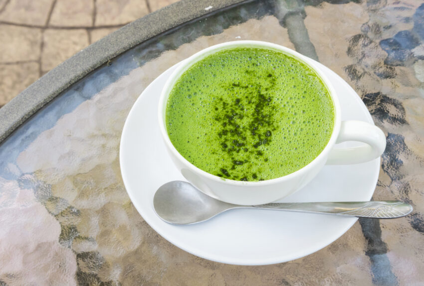 Closeup a cup of matcha latte or green tea on glass table