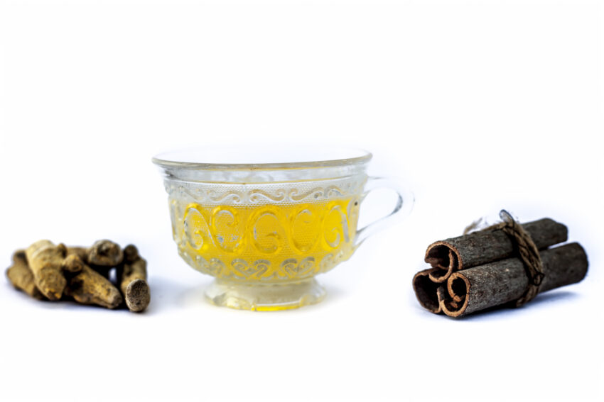 Popular turmeric tea isolated on white with its entire ingredients which are turmeric powder and raw, honey and cinnamon sticks.Used for detoxifying body.